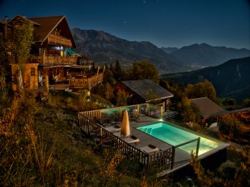 Piscine rectangulaire de nuit auprès d'un chalet à la montagne (crédit photo : Agnès Baudouin).