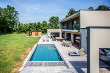The ipe deck subtly and elegantly highlights the pool installed in front of this Belgian house with its ultra-modern style.