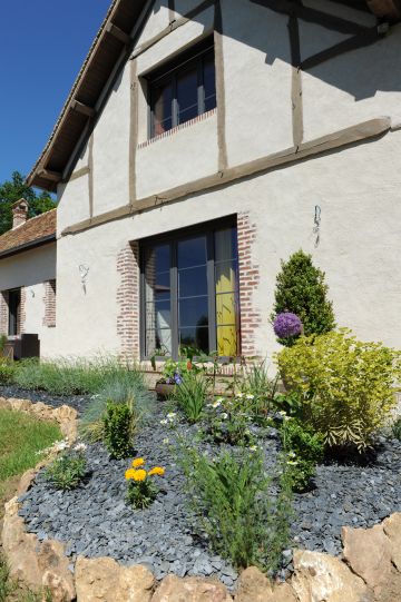 Les massifs paysagés bordent la longère et la piscine.