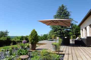 Entre des petits massifs paysagés, une belle terrasse en sapin et une longère traditionnelle normande Piscinelle a su construire un bassin intégré pour le plus grand bonheur des invités.