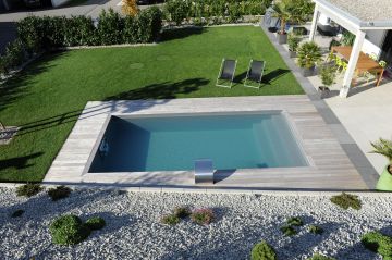 A rectangular pool in a garden between a lawn and gravelled area