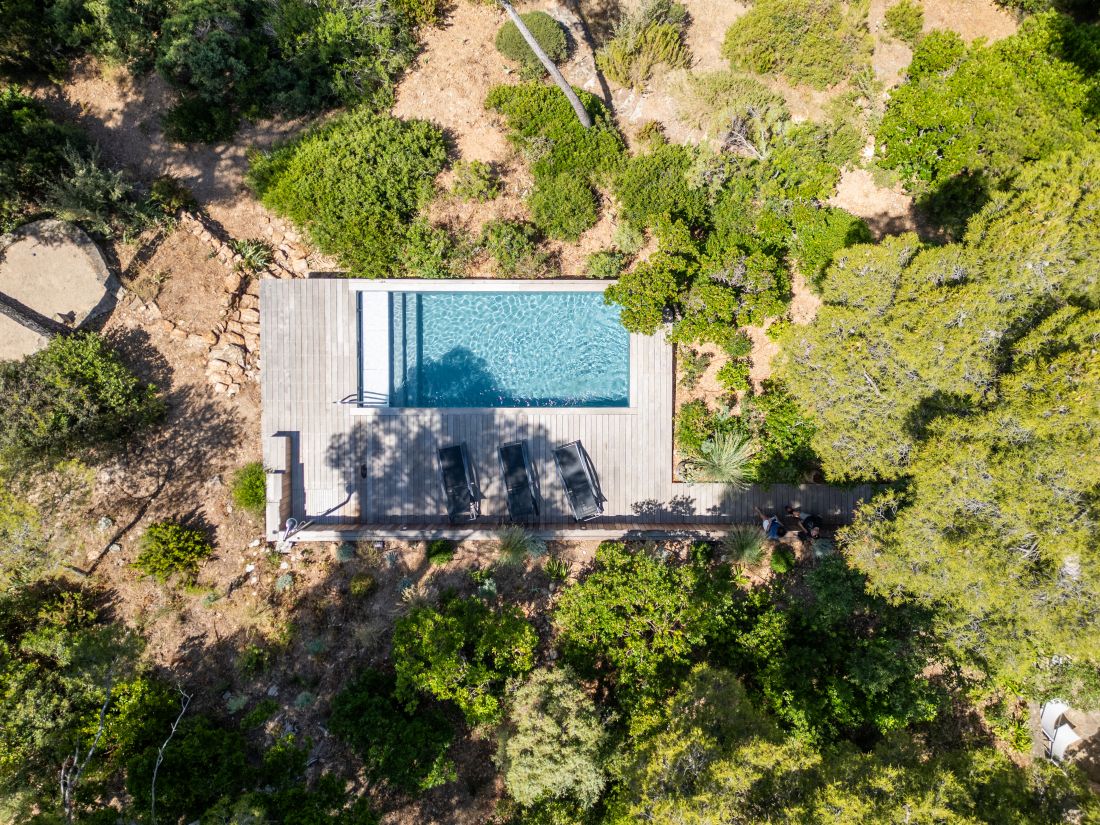 Piscine sur terrain en forte pente vue du ciel au milieu des pins - Piscinelle