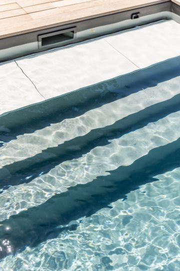 Escalier immergé et reflets dans l'eau de la piscine - Piscinelle