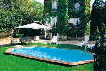 Piscine octogonale Rg entourée d'une pelouse en face d'une belle maison cachée par du lierre