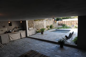 A covered space with a dining area opening out onto the pool