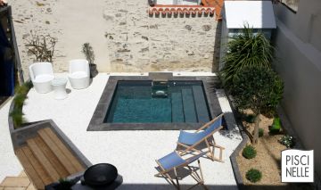 Small swimming pool with stone coping in the middle of a small garden in the city