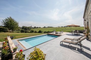 Au pied de la maison une superbe terrasse en pierre bleue de Belgique qui est alignée avec le Rolling-Deck de la piscine.