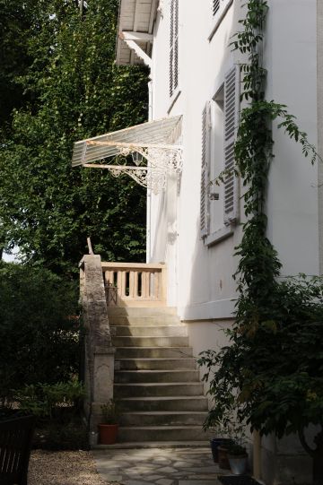 L'entrée de la maison de charme se fait en haut d'un escalier à l'abri d'une jolie marquise.