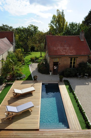 Entre la maison de maître et la maison de gardien, la piscine sait se faire discrète sous sa terrasse coulissante Rolling-Deck.